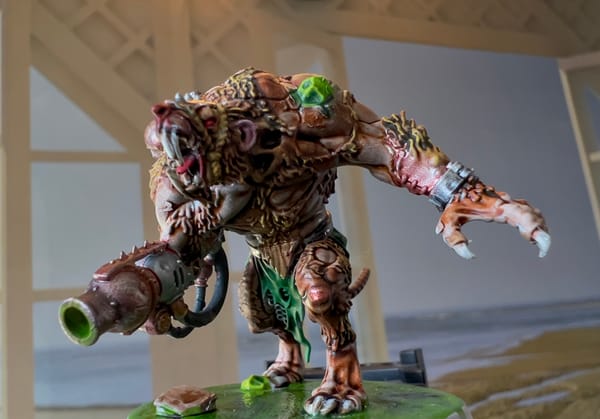 Painted miniature of a mutated rat-like creature with a large claw, metal arm cannon, and glowing green boils, standing snarling on a slime-covered base.