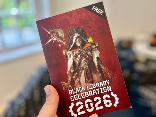 Hand holding a Warhammer 40,000 “Black Library Celebration 2026” book featuring a cybernetic priest illustration on a red background.